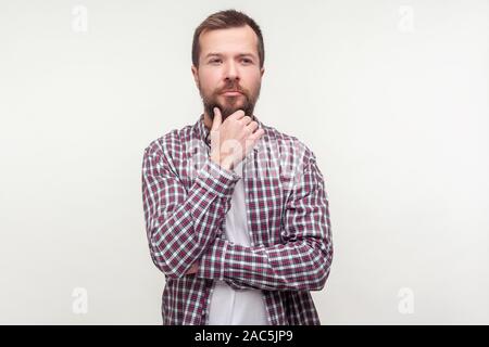 Lassen Sie uns Ihre Meinung! Portrait von nachdenklich, bärtigen Mann in Plaid Shirt sein Kinn nachdenken ernsthafte Idee berühren, die schwierige Entscheidung mit Zweifelhaft thoughtf Stockfoto