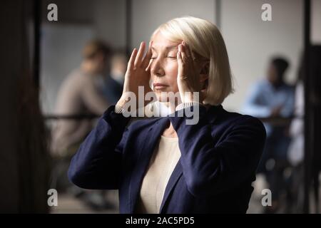 Kopf Nahaufnahme betonte im mittleren Alter Geschäftsfrau Schläfen massieren. Stockfoto