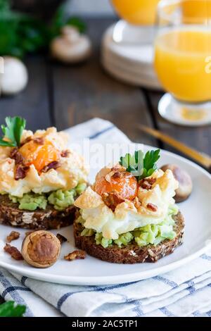 Sandwich mit Avocado und Orsini Ei auf Getreide Brot mit geröstetem Speck zum Frühstück. Leichte und gesunde Frühstück von einfachen Produkten. Comforta Stockfoto