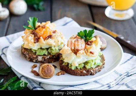 Sandwich mit Avocado und Orsini Ei auf Getreide Brot mit geröstetem Speck zum Frühstück. Leichte und gesunde Frühstück von einfachen Produkten. Comforta Stockfoto