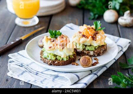 Sandwich mit Avocado und Orsini Ei auf Getreide Brot mit geröstetem Speck zum Frühstück. Leichte und gesunde Frühstück von einfachen Produkten. Comforta Stockfoto