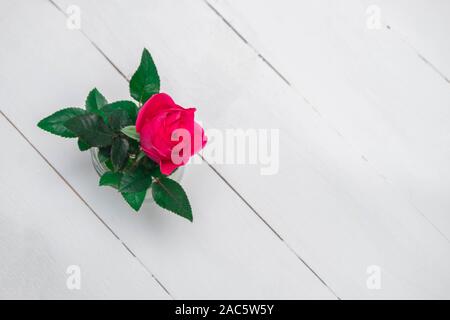 Blick von oben auf die Single rosa Rose in ein Glas Rose auf weiße Holztisch Stockfoto