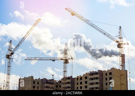 Im Bau Hochhaus mit gelben Baukran im Sonnenlicht. Rohr anlage Umweltverschmutzung. Stockfoto