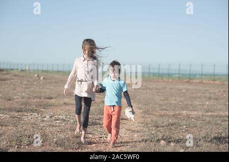 Flüchtling verwaiste Familie Junge und Mädchen Hand in Hand gehen in der heißen Wüste in der Nähe der Staatsgrenze Stockfoto