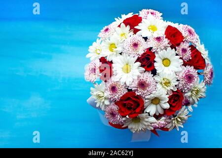 Schöne rote Rosen und zarte Chrysanthemen auf blauem Hintergrund. Wunderbare Blumen und kopieren Sie Platz für Text. Stockfoto