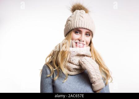 Winter Nahaufnahme Porträt der attraktive junge blonde Frau in Beige warme Strickmütze mit Fell pompom und Schal snood. Mädchen mit Kamera auf wh Stockfoto