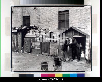 Hütten und Arbeitslose, West Houston und Mercer Street, Manhattan Code: III.G Männer teilen ein Licht vor der Hütte mit offener Tür, Milch und waschtrog Innen, Hütte zu verlassen hat Bilder in Frames schmücken die von ausserhalb. Zitat/Bezug: CNY #36; Hütten und Arbeitslose, West Houston und Mercer Street, Manhattan. Stockfoto