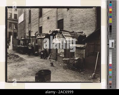 Hütten und Arbeitslose, West Houston und Mercer St, Manhattan Code: III.G. Männer sitzen vor Hütten aus geborgen Materialien, teilweise mit Bildern dekoriert, Katze spielt vor in der Nähe von Kinderwagen. Zitat/Bezug: CNY #35; Hütten und Arbeitslose, West Houston und Mercer Street, Manhattan. Stockfoto