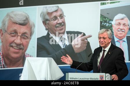 Wiesbaden, Deutschland. 01 Dez, 2019. Volker Bouffier (CDU), Ministerpräsident von Hessen, spricht anlässlich der Preisverleihung. Die Wilhelm Leuschner Medaille 2019 wird posthum an Walter Lübcke (CDU), ehemaliger Präsident des Kasseler Regierung, die im Juni erschossen wurde ausgezeichnet. Im Hintergrund Fotos von Walter Lübcke werden angezeigt. Der Preis wird an Personen, die einen besonderen Beitrag zur Demokratie verdient gemacht haben. Credit: Andreas Arnold/dpa/Alamy leben Nachrichten Stockfoto