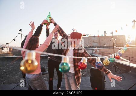 Heraus hängen. Urlaub auf dem Dach. Fröhliche Gruppe von Freunden hoben ihre Hände mit Alkohol Stockfoto