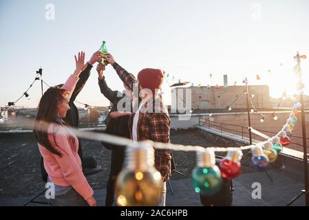 Strahlender Sonnenschein. Urlaub auf dem Dach. Fröhliche Gruppe von Freunden hoben ihre Hände mit Alkohol Stockfoto