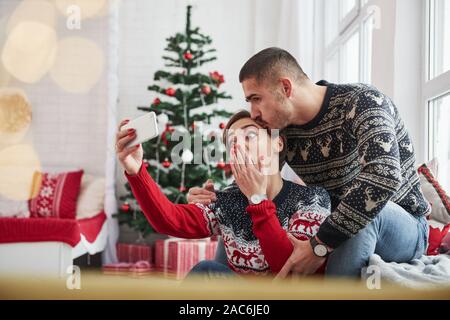 Emotionale Mädchen möchten lustiges Foto. Gerne jungen Menschen sitzt auf der Fensterbank im Zimmer mit Weihnachtsschmuck Stockfoto