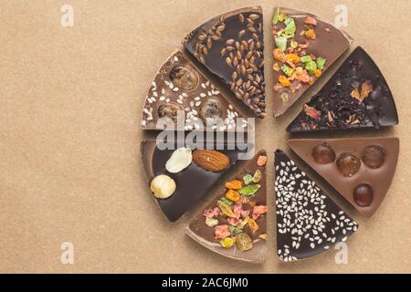 Stücke Schokolade für das Handwerk Papier, Pergament. Art Design. Dunkle Schokolade gewürzt. Essen Hintergrund. Scheiben schwarz und Milchschokolade mit Süßigkeiten, ra Stockfoto