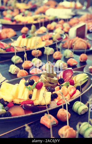 Früchte, Patty Kuchen und kleine Snacks an Voll gedeckten Tisch in einem Restaurant, getönten Bild Stockfoto