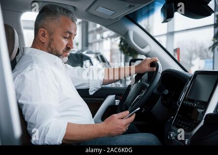 Mit Handy. Geschäftsmann sitzt in der modernen Auto und haben einige Geschäfte Stockfoto