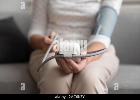 Closeup alte Frau nimmt manuell Blutdruck mit Sphygmomanometer Stockfoto