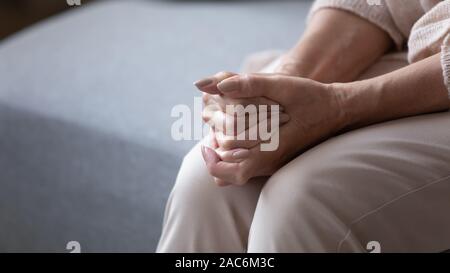 Ältere Frau sitzt im Innenbereich gefaltet Palmen in runde Gefühl der Einsamkeit Stockfoto