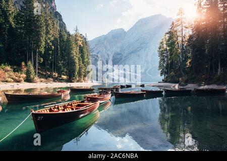Das Sonnenlicht wird über die Bäume. Verbunden Boote auf dem Wasser in der Nähe vom Wald und den majestätischen Berg Stockfoto