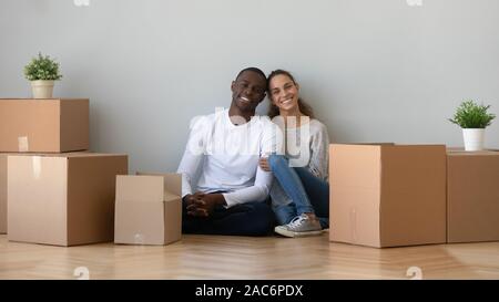 Glücklich lächelnde junge gemischte Rasse Familie Paare sitzen auf dem Boden. Stockfoto