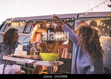 Gerne Freunden zujubeln, Wein trinken und beim Camping Urlaub am Strand mit Vintage van. Menschen Spaß am Wochenende Sommer Abend mit Campe Stockfoto