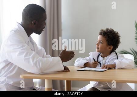 Glückliche kleine Patienten Ärzte gleichmäßige Beschichtung mit dem Kinderarzt. Stockfoto