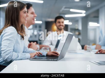 Seitliche Sicht auf Mädchen arbeitet auf der silbernen Laptop im Büro und lächelnd Stockfoto