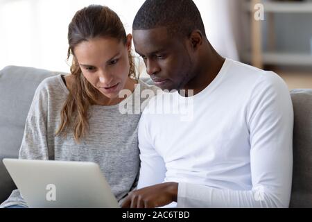 Fokussierte Ehemann seine Frau interessiert neue Online-Banking-Anwendung angezeigt. Stockfoto