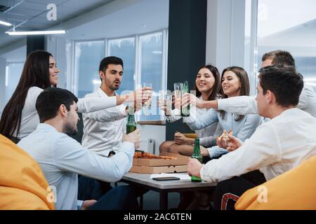 Für unsere Zukunft. Feiern erfolgreichen Abschluss. Junge Berufstätige sitzt in der Nähe des Tisches mit Alkohol Stockfoto