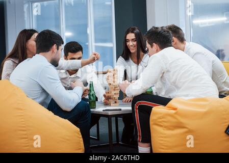 Schönen Abend in guter Gesellschaft. Feiern erfolgreichen Abschluss. Junge Berufstätige sitzt in der Nähe des Tisches mit Alkohol Stockfoto