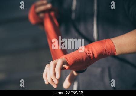 Nahaufnahme der jungen männlichen Händen mit dem Boxen Bands. Junge bereitet für einen Safe Training durch seine Hand wickeln. Boxer bereit, Schläge zu werfen. Teenager Spor Stockfoto