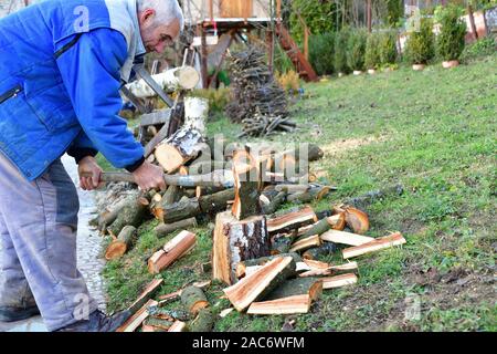 Woodcutter schneidet Holz mit einer Axt im Garten des Dorfes Stockfoto