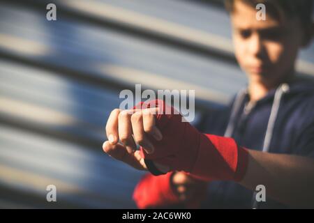 Nahaufnahme der jungen männlichen Händen mit dem Boxen Bands. Junge bereitet für einen Safe Training durch seine Hand wickeln. Boxer bereit, Schläge zu werfen. Teenager Spor Stockfoto