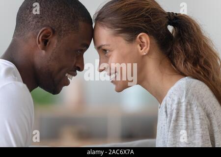 Glücklich lächelnde zärtlich gemischten Rennen Familie Paar Stirn zu berühren. Stockfoto