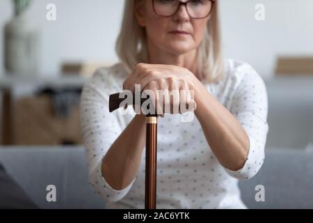 Frau mittleren Alters auf der Couch Holding in den Händen Zuckerrohr eingesetzt Stockfoto