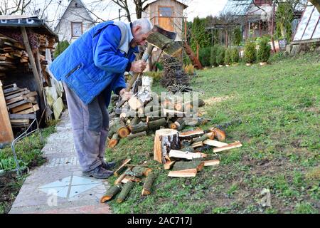 Woodcutter schneidet Holz mit einer Axt im Garten des Dorfes Stockfoto