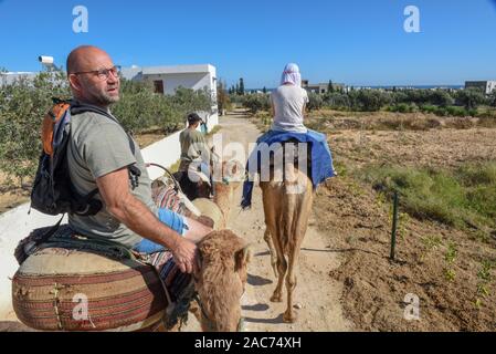 Sousse, Tunesien - 8 November 2019: Touristen auf einer Kamelkarawane in Sousse in Tunesien Stockfoto