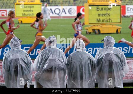 Olympiastadion München Deutschland 6.8.2002, Europäische Leichtathletik WM, die Beamten, die Sie in einem Rennen von sintflutartigen Regenfällen durch Regen Capes geschützt Stockfoto