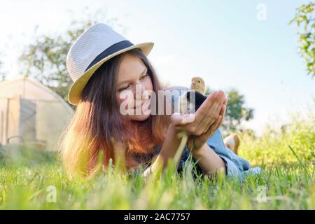 Outdoor Portrait von schönen lächelnden Teenager auf Bauernhof mit zwei neugeborene Küken in der Hand, Natur Hintergrund grün gras himmel Stockfoto