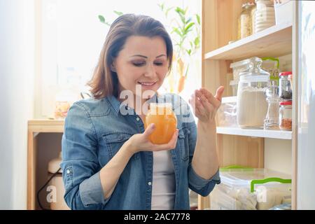 Frau mit Krug golden Organische frische Honig in der Küche in der Nähe von essen Lagerregal Stockfoto