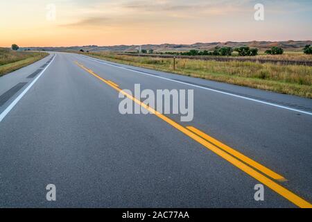 Leere Autobahn und Bahnschienen entlang einer Tal der mittleren Loup River in Nebraska Sandhills, Spätsommer Landschaft vor Sonnenaufgang, Travel Concept Stockfoto