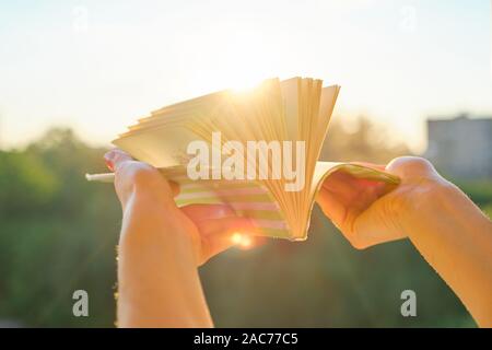 In der Nähe von buchen Sie im womans Hand, Hintergrund, Sonnenuntergang, abend stadt Stockfoto