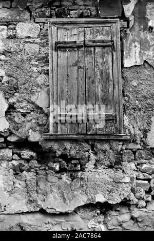 Texturierte Wand der alten heruntergekommenen Haus mit Fenster mit Fensterläden geschlossen. Schwarze und weiße architektonisches Detail Stockfoto