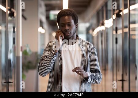 Konzentriert afrikanische Unternehmer wandern im Büro Flur am Telefon sprechen Stockfoto