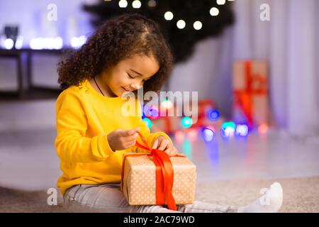 Cute afrikanischen kid Eröffnung Weihnachtsgeschenk zu Hause Stockfoto