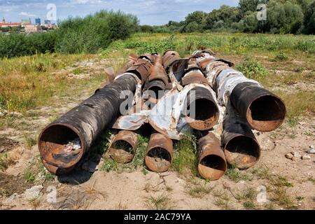 Haufen altes rostiges Metall Rohre links am Flussufer Feld Stockfoto