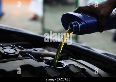 Mechaniker gießt Motor Öl in den Motor aus blauem Kunststoff Behälter Stockfoto
