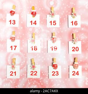 13-24 Teil der Adventskalender mit Zahlen auf weiße Laken auf dekorative Clips auf Weiß-Rot snowy Hintergrund. Weihnachten festliche Dekorationen. Stockfoto