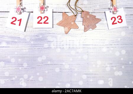 21-23 Teil der Adventskalender mit Zahlen auf weiße Laken auf dekorative Clips und Holz- Weihnachten Spielzeug auf weißem Holz- snowy Hintergrund mit Kopie sp Stockfoto