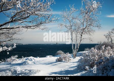 Die verschneite Küste bei Fort Williams Park und Ram Island riff Licht station in Portland Maine an einem sonnigen blauen Himmel. Stockfoto