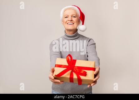 Gerne ältere Dame in rot Mütze holding Geschenkbox Stockfoto